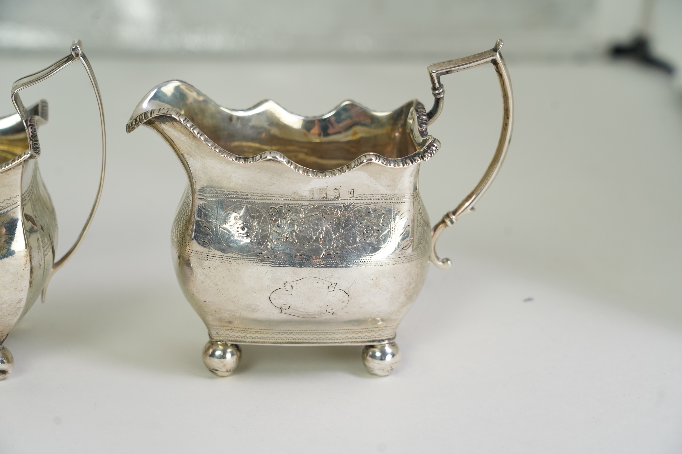 A George III Irish silver two handled sugar bowl, by Richard Sawyer, Dublin, 1808, 18.4cm over handles, with engraved armorial, on four ball feet, together with a similar cream jug, by Daniel Egan, Dublin, 1811, 16.2oz.